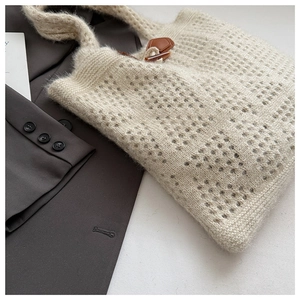 Close-up of beige knit tote bag featuring a vintage toggle clasp and textured mesh fabric