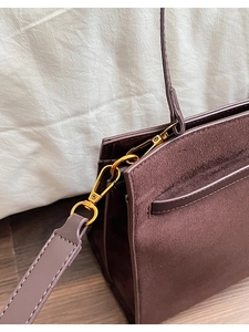 Vue détaillée du fermoir mousqueton doré sur un sac cabas en daim de couleur chocolat
