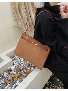 Détail du sac cabas en daim marron avec sangle en cuir et fermoir rotatif en métal doré