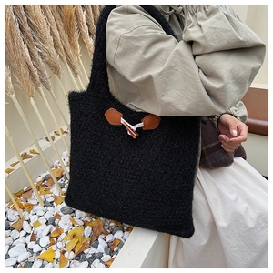 Detail of plush black knit tote bag featuring a classic toggle button and leather patch