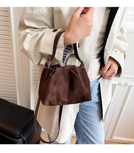 Detail of dark brown suede handbag with pleated design and adjustable leather shoulder strap