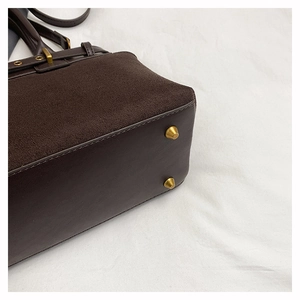 Detail shot of brown suede and leather stitching with golden metal feet on the bottom