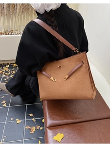 Détail du sac cabas en daim marron avec fermoir tournant en métal et bandoulière en cuir