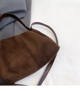 Detail shot of the dark brown suede texture and slim leather strap on a cloud bag