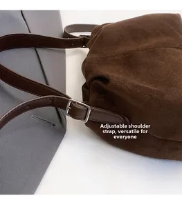 Detail of adjustable leather strap and metal buckle on dark brown suede cloud bag