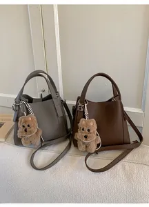 Detail of taupe and brown bucket bags with pebble texture and plush puppy charm