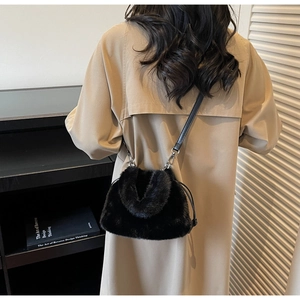 Détail du sac seau en peluche noire avec bandoulière en cuir et boucle en métal argenté