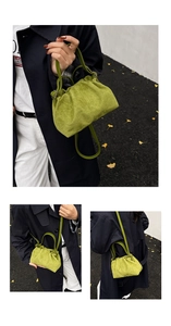 Three-way carry view of a pleated green cloud bucket bag in a stylish autumn street setting