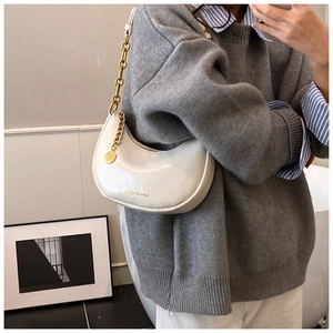 Lifestyle shot of white hobo crescent bag with gold chain and crinkled texture