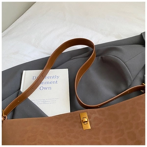 Leopard print suede tote bag with vintage gold turn-lock closure on gray suit