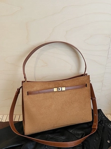 Sac cabas en daim marron avec lanières en cuir et boucle en métal sur fond sombre