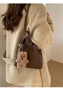 Detail of dark brown leather bucket bag with litchi texture and plush dog charm