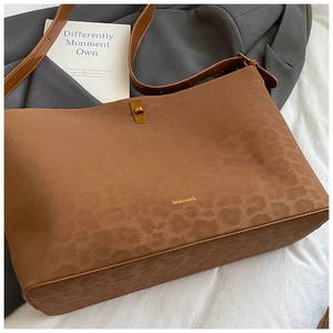 Close-up of leopard print suede tote with golden buckle and adjustable strap detail