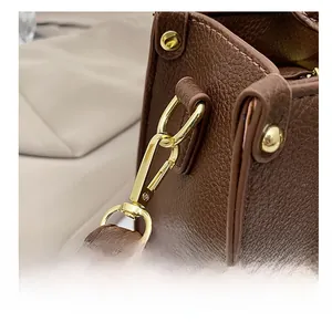 Detail of premium golden lobster clasp and brown lychee textured leather on a tote bag