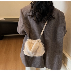 Détail du sac seau en peluche crème avec cordon de serrage sur un blazer gris