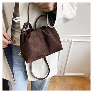 Close-up of minimalist brown suede cloud bag with pleated closure and adjustable strap