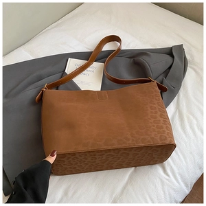 Detail shot of a large brown leopard print suede tote bag on a grey coat with a card