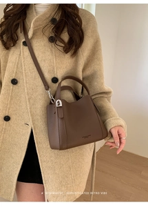 Detailed view of dark brown pebbled leather handbag with fine stitching and gold hardware
