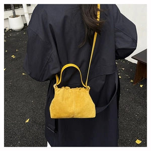 Fashionable bright yellow suede cloud bag with drawstring closure on dark coat model