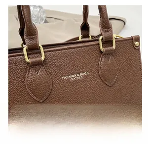 Detail of brown litchi grain leather handbag with gold metal rings and fine stitching