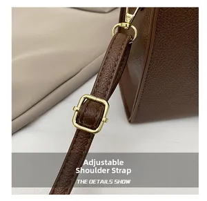 Detail of adjustable leather shoulder strap with gold-tone buckle on dark brown bag