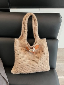 Light brown cable knit tote bag with horn buckle on leather chair background
