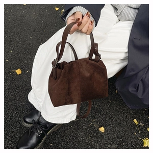 Detail of dark brown corduroy bag with leather handle on an autumn street background