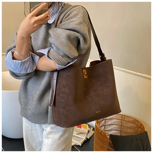 Detailed view of brown suede shoulder bag with gold metal twist lock and textured finish