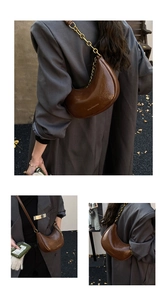Detail of brown crescent moon bag with glossy leather, gold chain, and crossbody strap