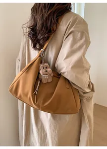 Detalle de bolso tote marrón con correa ajustable y un bonito colgante de oso de peluche