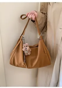 Detalle del bolso tote de cuero caramelo con correa ajustable y colgante de felpa
