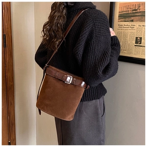 Détail d'un sac seau en daim marron avec bandoulière en cuir et boucle argentée