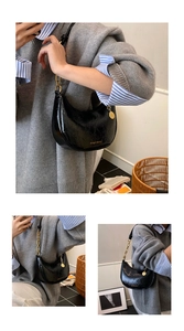 Detail of black glossy croissant bag with gold chain strap and moon-shaped design