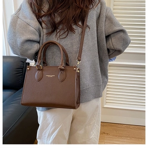 Brown lychee leather handbag featuring gold hardware and a classic trapezoid shape