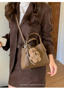 Detailed texture of brown pebble leather bucket bag with cute bear charm and logo