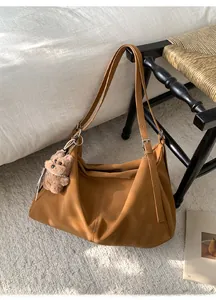 Detalle de un bolso hobo grande color caramelo con colgante de osito de peluche