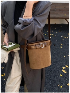 Détail d'un sac seau en daim marron avec bandoulière en cuir et boucle argentée