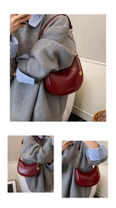 Detail of burgundy crescent bag featuring glossy cracked leather and gold chain accent