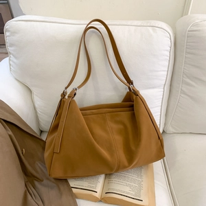 Detalle del bolso tote grande marrón camello en cuero sintético mate sobre sofá blanco