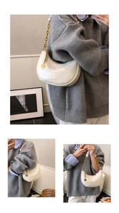 Detail of cream half-moon bag featuring textured leather and a chunky gold chain strap