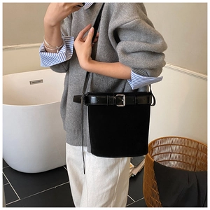 Détail d'un sac seau noir avec texture mate et boucle métallique décorative de ceinture