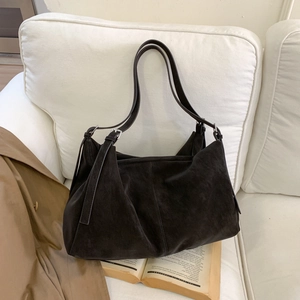 Bolso tote grande de ante marrón oscuro sobre un sofá blanco para uso diario y ocio
