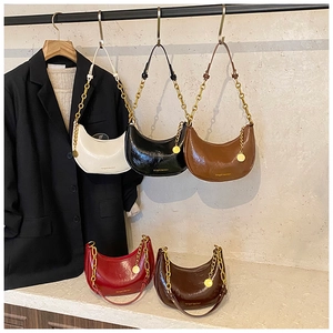 Detailed close-up of crescent hobo bags with shiny oil-wax texture and gold chain straps