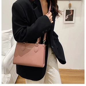 Detail of pink pebbled leather handbag with gold hardware and embossed fashion logo