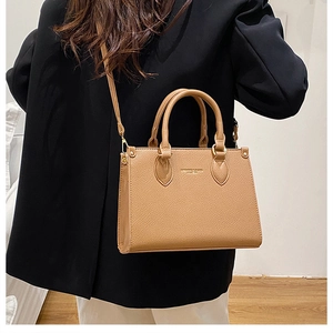 Detail of camel brown pebbled leather tote with top handles and adjustable shoulder strap