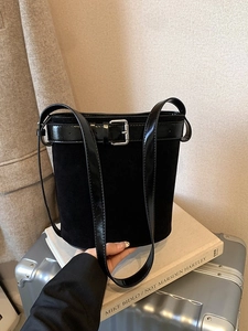 Sac seau chic en daim noir et cuir verni présenté dans un décor de style de vie intérieur