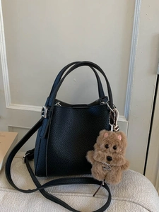 Minimalist black lychee texture handbag with plush dog charm and adjustable shoulder strap