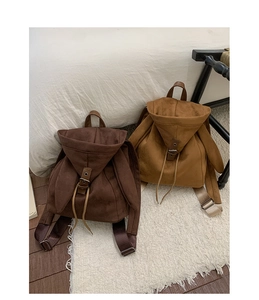 Detail of dark brown and ginger faux suede backpacks featuring drawstring and buckle closures