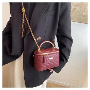 Close-up of wine red quilted bag with gold chain strap and adjustable ball buckle