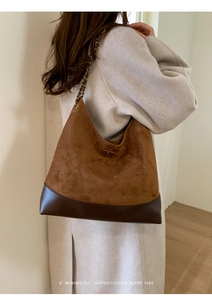 Detail der braunen Hobo-Tasche mit Steppmuster und Kettengurt auf einem beigen Mantel